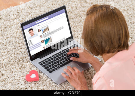 Close-up di donna con cuore sign in chat sul sito di social networking su laptop Foto Stock