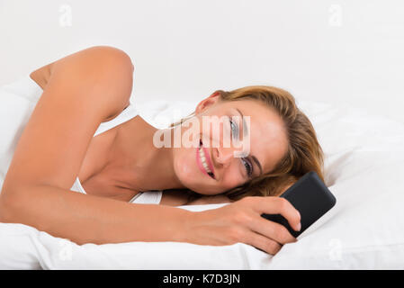 Ritratto di giovane donna felice tenendo il telefono cellulare Foto Stock