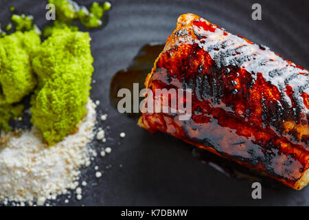 Grigliata di anguilla affumicata con mela verde e agrumi sulla piastra nera Foto Stock