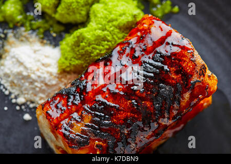 Grigliata di anguilla affumicata con mela verde e agrumi sulla piastra nera Foto Stock