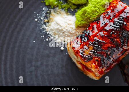 Grigliata di anguilla affumicata con mela verde e agrumi sulla piastra nera Foto Stock