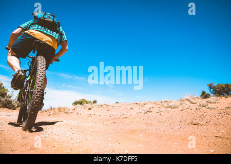 Sezione bassa vista posteriore del senior uomo Bicicletta Equitazione su strada sterrata contro il cielo blu Foto Stock