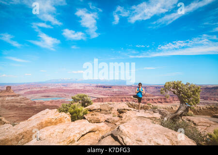 Donna matura di eseguire lo yoga nella struttura ad albero pongono sulla montagna contro il cielo blu Foto Stock