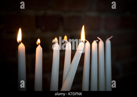 Close-up di candele accese in camera oscura contro un muro di mattoni durante Hanukkah Foto Stock