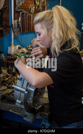 La rottura degli stereotipi - ragazza adolescente lavorando sul motociclo rotto il motore a officina meccanica Foto Stock