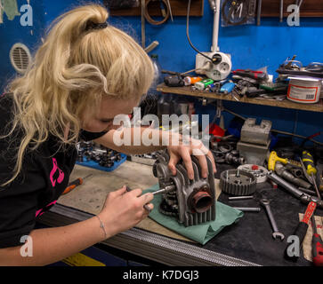 La rottura degli stereotipi - ragazza facendo lavoro maschio a officina meccanica. giovane donna rotto riparazioni motore del motociclo Foto Stock