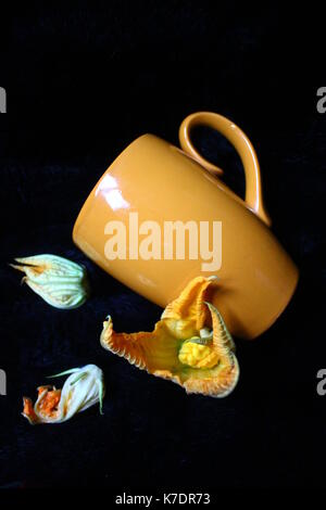 Colore arancio tazza di argilla per caffè giaceva sul pelo nero decorato con fiori di bloom Foto Stock