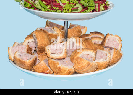 Tagliare la carne di maiale torte e insalata presentato su un supporto isolato su uno sfondo blu Foto Stock