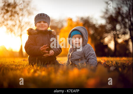 I fratelli seduti nel campo in autunno Foto Stock