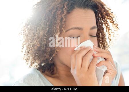 Metà donna adulta soffia il naso sul tessuto. Foto Stock