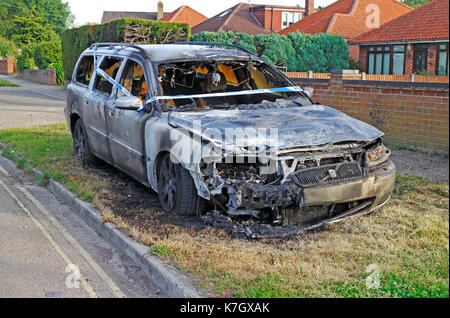 Un bruciato auto con nastro di polizia sul ciglio della strada a Hellesdon, Norfolk, Inghilterra, Regno Unito. Foto Stock