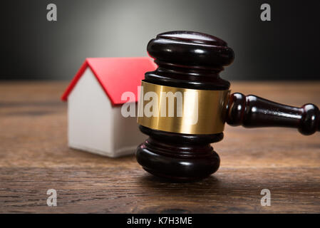 Close-up del modello di casa con martello sul tavolo di legno Foto Stock