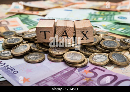 Close-up di blocchi di legno con la parola tassa sulla moneta in euro Foto Stock