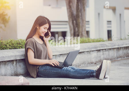 Tecnologia di uno stile di vita moderno, asian carino teen donne chiamando con lo smartphone e utilizzando il computer portatile la felicità e il sorriso di godere in campus. Foto Stock