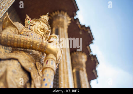 Angolo basso di una statua guardiana del demone d'oro fuori Phra Mondop a Wat Phra Kaew (Tempio del Buddha di Smeraldo). Il Grand Palace, Bangkok, Thailandia Foto Stock