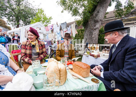 Inghilterra, Chatham Dockyard. Evento, salutare per gli anni quaranta. Due coppie di picnic esterno insieme seduti attorno al tavolo di gioco in chat. Tutti vestiti in classe superiore 1940 costume. Foto Stock