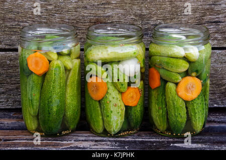 Aperte tre vasi di vetro di cetrioli sottaceto rustico di legno. Foto Stock