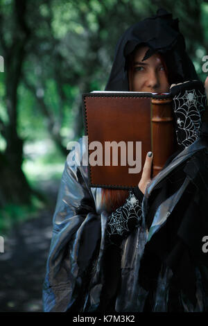 Immagine della strega incantesimo di lettura dal Libro nella foresta di mistico Foto Stock