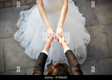 Giovani asiatici sposa e lo sposo tenendo le mani e ballare, ad alto angolo di visione. Foto Stock