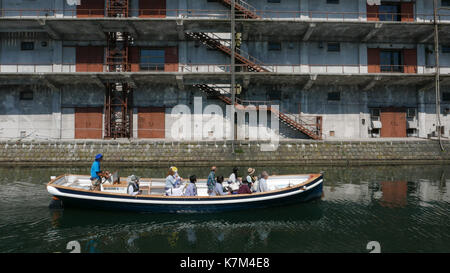 Tour in barca passando di fronte hokkai storica fabbrica può costruire in otaru giappone ombra della barca e di costruire in canal nessuno guardando la fotocamera. Foto Stock