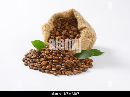 Tela sacco pieno di chicchi di caffè su sfondo bianco Foto Stock