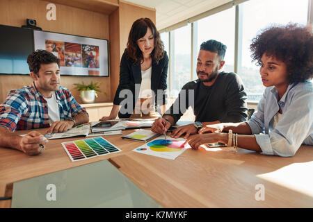 Gruppo di progettisti creativi team a discutere di progetto, scegliere lo schema di colori posa campioni nella sala conferenza. Foto Stock