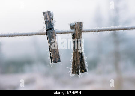 Due pioli di vestiti coperti di gelo all'aperto su una linea Foto Stock