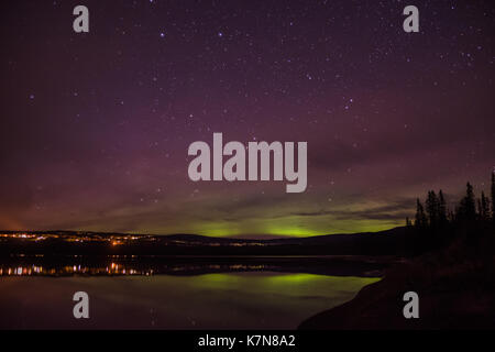 Aurora borealis luci che ballano sul villaggio e sul lago Foto Stock