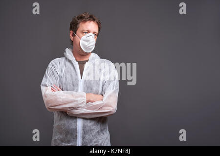 Un uomo di mezza età in piedi in una maschera e in un vestito di protezione Foto Stock