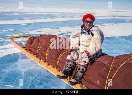 Locale donna inuit sambuco, vestito di Caribou Coffee Company tradizionale abbigliamento di pelle, seduti su una tradizionale inuit cargo sled, chiamato anche komatik. Indossa il cappotto 'lato dei capelli in cui è impiegato per calore supplementare. Foto Stock