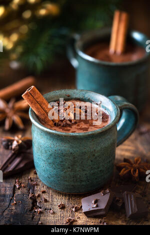 Cioccolata calda con un bastoncino di cannella, stella di anice e cioccolato grattugiato topping nella festa di Natale impostazione su scuri in legno rustico sfondo Foto Stock
