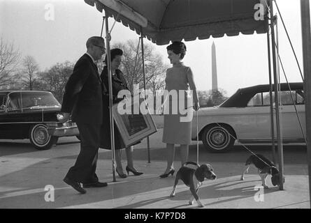 Lady Bird Johnson (centro) e sua figlia Luci Baines Johnson, tenendo il guinzaglio del cane di famiglia (a destra), sono accompagnati dalla Casa Bianca usher J.B. Ovest come si muovono nella Casa Bianca di Washington, DC, 12/07/1963. Foto Stock