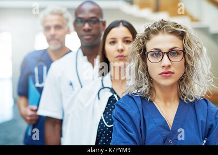 Malinconici team di medici guardando la fotocamera in piedi in un ospedale. Foto Stock