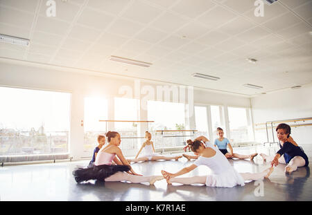 Gruppo di ballerini seduto e stretching sul pavimento facendo leg split con insegnante nella classe di balletto. Foto Stock