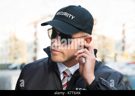 Ritratto di giovane maschio guardia di sicurezza ascolto di auricolare Foto Stock