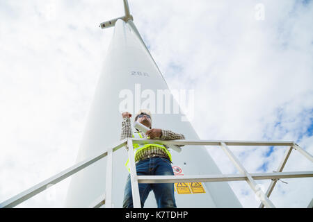 Ingegnere di lavoro al sito della turbina eolica con blueprint Foto Stock