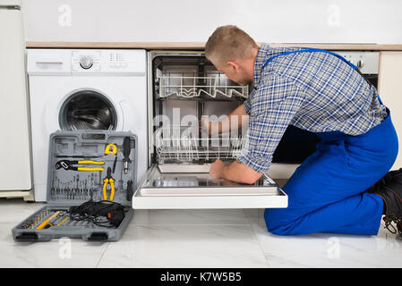 Giovane uomo in generale con toolbox riparazione di lavastoviglie Foto Stock