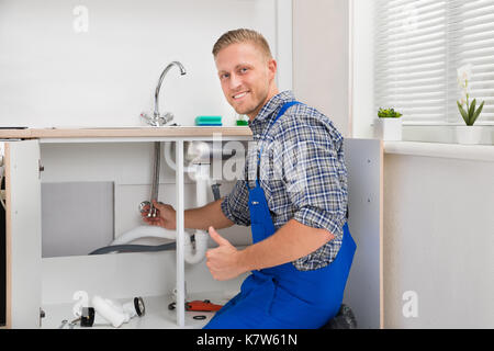 Felice idraulico maschio riparazione rubinetto nel lavello da cucina Foto  stock - Alamy