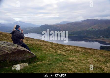 Lone lady fellwalker prendendo una pausa sul hause cancello sul percorso verso la wainwright hill catbells affacciato derwentwater nel distretto del lago. Foto Stock