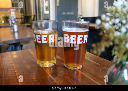 Due pinte di birra "' bicchieri in un pub. shallow focus sui bicchieri. Londra, Regno Unito. Foto Stock