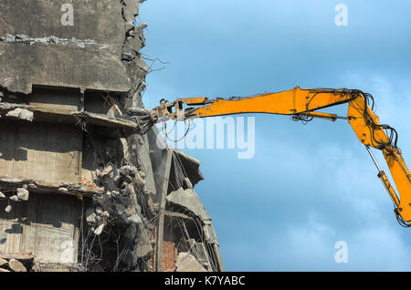 Rimozione di un edificio in cemento armato in un'area urbana con un escavatore Foto Stock