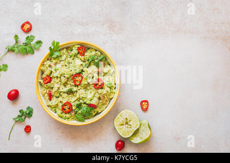 Guacamole fresco dip con ingredienti sulla pietra rustica sfondo. vista dall'alto, un sacco di spazio di copia Foto Stock