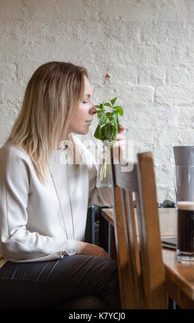 I giovani adulti bionda capelli lunghi lieti donna odora di menta fresca. unposed candidi colpo verticale Foto Stock