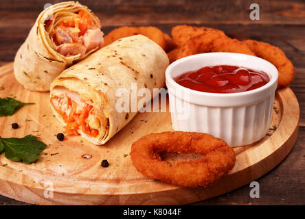 Shaurma con pollo fritto con anelli di cipolla su una tavola di legno. La birra snack. Foto Stock