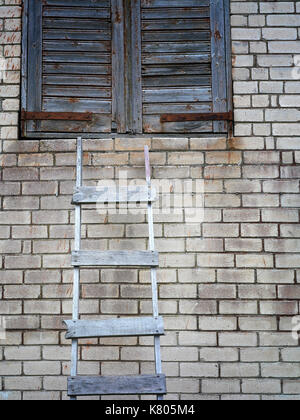 Vecchia scala di legno e muro di mattoni con chiudi finestra sulla parte superiore, verticale foto ritagliata Foto Stock