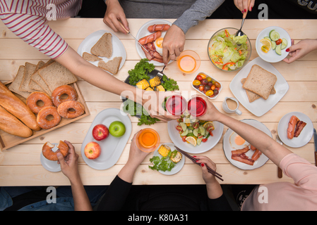 Godendo di una cena con gli amici. vista dall'alto del gruppo di persone a cena insieme mentre è seduto al tavolo di legno Foto Stock