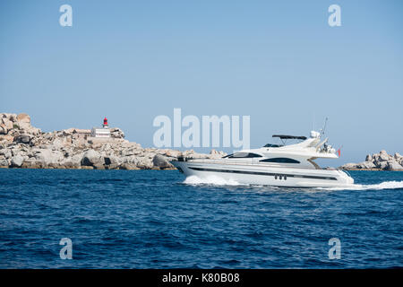 Piccola imbarcazione a motore vicino all isola di Lavezzi con il faro in background, Francia Foto Stock