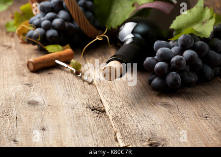 Bottiglia di vino e di uve nel cestello sul vecchio sfondo di legno Foto Stock