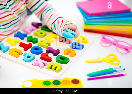 Bambino facendo i compiti per la scuola al bianco scrivania in legno per istruzione abc puzzle giocattoli per bambini. Felice torna a scuola studente. kid alfabeto di apprendimento lettere Foto Stock