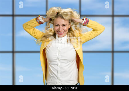 Donna sorridente tenendo le mani nei capelli. Foto Stock